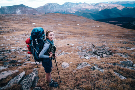 A young female hiker smiles at the summit of a mountain pass