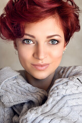 Portrait of a beautiful young red-haired woman with short hair wearing warm woolen sweater