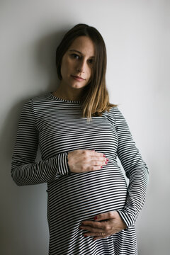 Portrait of a pregnant woman touching her belly.