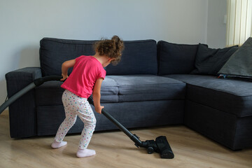 child with vacuum cleaner cleaning the parquet floor at home