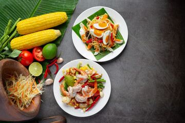 Som Tum with Corn and Shrimp, served with rice noodles and green salad Decorated with Thai food ingredients.