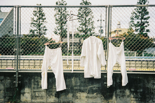 White Kimonos Drying on Coat Hangers Hanging on Fence