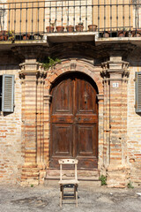 detail of the entrance of a building with a chair in front, Offida, Ascoli Piceno, Umbria, Italy