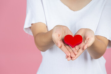 World diabetes day; hand holding red heart on pink background