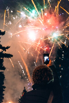 Woman taking photos of fireworks using smartphone