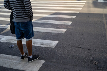 Man in short jeans and stripes blouse waiting at a pedestrian crossing. - 379871526