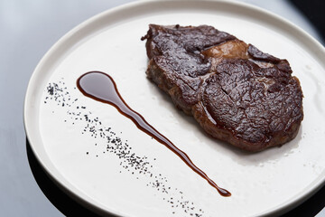 Rib eye steak on white plate, close-up. Sliced tenderloin steak