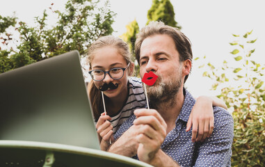 Father and daughter having fun while video chat on laptop computer
