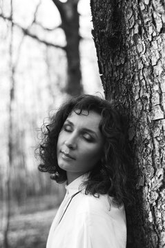 A portrait of a beautiful woman nearby tree with a closed eyes