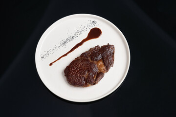 Rib eye steak on white plate, close-up. Sliced tenderloin steak