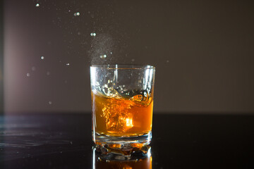 Shot of whiskey with splash on black background