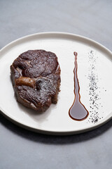 Rib eye steak on white plate, close-up. Sliced tenderloin steak