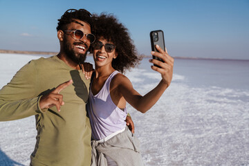 Image of happy african american couple taking selfie on mobile phone