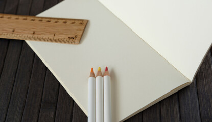 Colored pencils next to ruler and blank notebook