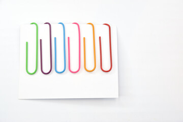 A set of colored paper clips attached to a note sheet