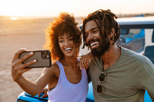 Image of african american couple taking selfie on cellphone in desert