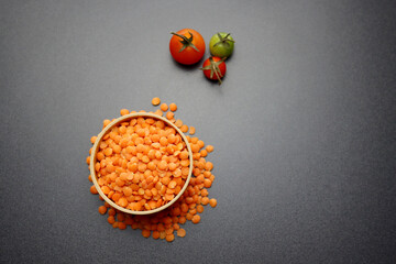 Obraz na płótnie Canvas Red lentils in a round wooden bowl on a gray background.