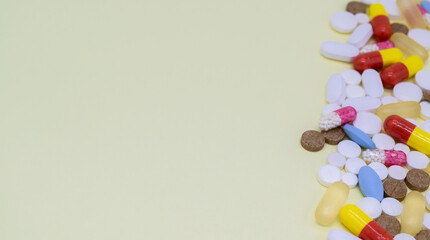 Close up of colorful tablets and pills on the right. Yellow background, copy space