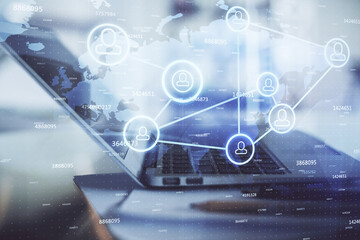 Obraz premium Computer on desktop with social network hologram. Double exposure. Concept of international people connections.