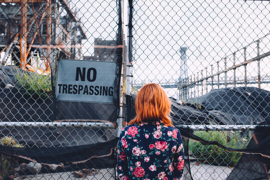 woman in front of a ""no trespassing"" sign
