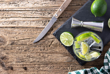 Caipiroska cocktail with lime on wooden table. Top view. Copy space	