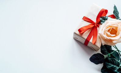 rose flower and handmade gift box decorated with red bow, wrapping paper on white background....