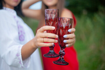 Glasses with wine in the hands of the girls. 