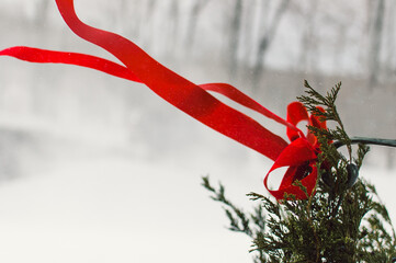 red ribbon on Christmas wreath blowing in snow