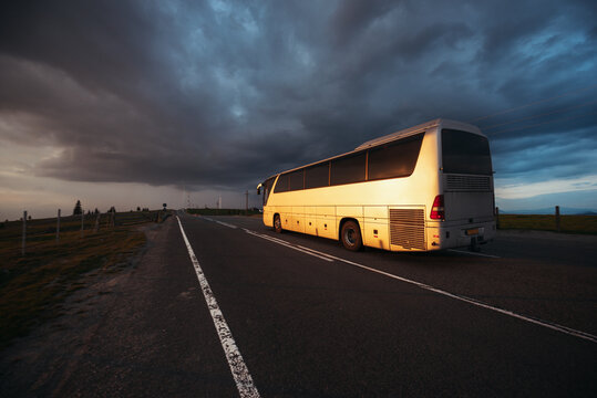 Bus driving on the road at sunset