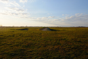 Fototapeta premium Hill in the field. Yellowed grass. Evening sky over the field.