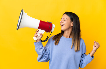 Caucasian girl isolated on yellow background shouting through a megaphone to announce something in lateral position