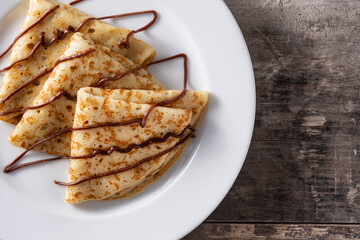 Sweet crepes with chocolate on wooden table. Copy space	