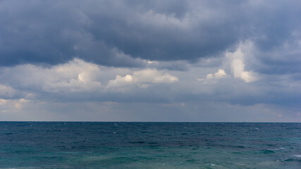 Obraz premium dramatic clouds in the sky over the sea, before the rain, heavy weather, grey clouds, turquoise ocean, soft focus, film noise