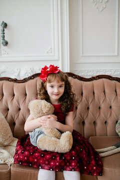 Little girl with teddy bear is looking at the camera