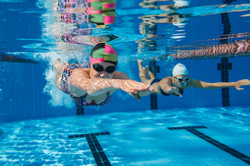 Caucasian female swimmers propelling underwater while competing