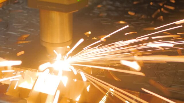 Metalworking, equipment, machining, industrial, technology, manufacturing concept. Automatic cnc laser cutting machine working with sheet metal with sparks at factory, plant - close up