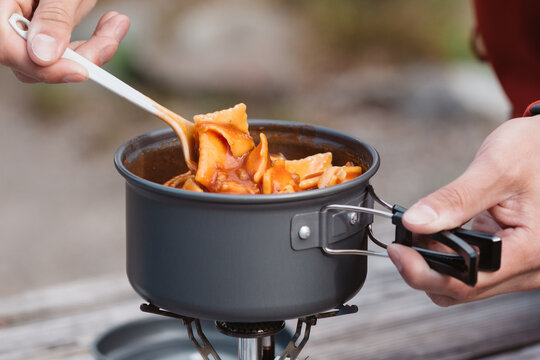 Stirring food in kettle on backpacking stove.