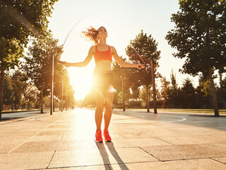 Athletic woman with jumping rope training in park.