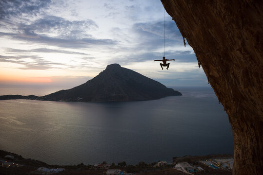 Rock climber silhouette hanging with arms outstretched