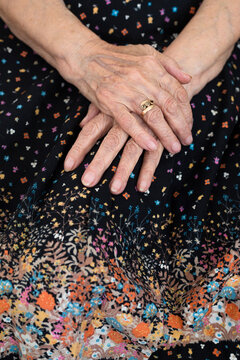 Hands of an elderly woman crossed on top of her skirt
