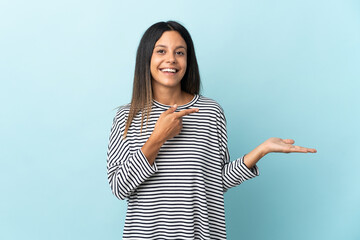 Caucasian girl isolated on blue background holding copyspace imaginary on the palm to insert an ad