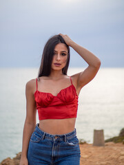 Mujer joven posando con el mar de fondo durante el atardecer