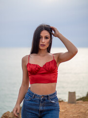 Mujer joven posando con el mar de fondo durante el atardecer