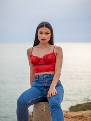 Mujer joven posando con el mar de fondo durante el atardecer