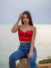 Mujer joven posando con el mar de fondo durante el atardecer