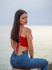 Mujer joven posando con el mar de fondo durante el atardecer