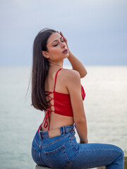 Mujer joven posando con el mar de fondo durante el atardecer