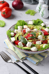 Healthy salad with avocado, tomatoes, feta and red onion on grey background, closeup