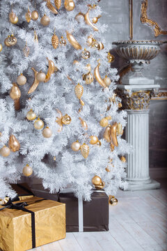 Golden christmas toys hanging on white artificial christmas tree