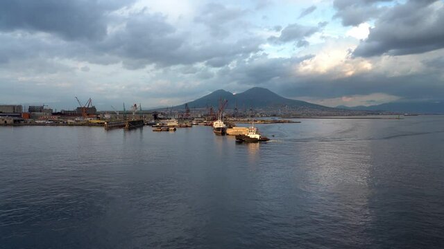Shipyard in Naples harbor with Vesuvius volcano at sunset in Italy. 4k footage.